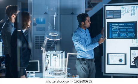 Engineers Meeting in Technology Research Laboratory: Male Engineer Leads Presentation Using Digital Whiteboard, Shows Machine Blueprint, Data Analytics and Neural Network while Colleagues Listening - Powered by Shutterstock