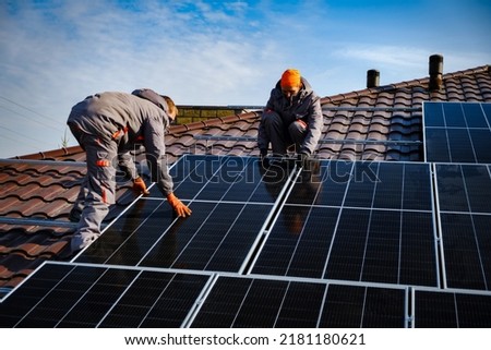 Engineers on the roof of house are checking solar cells in the autumn. Technician worker on solar panels
