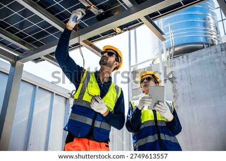Engineers perform electrical testing on photovoltaic panels at a rooftop solar power installation. The technicians maintain renewable energy systems to ensure stable electricity generation.