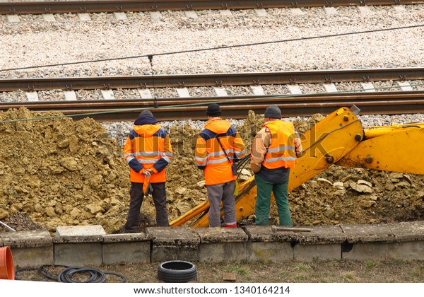Engineers and railway workers repair the track
using an excavator. Infrastructure of the transport communication
node. Digging special equipment. Equipment for the protection of
workers at risk.