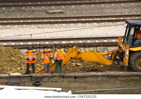 Engineers and railway workers repair the track
using an excavator. Infrastructure of the transport communication
node. Digging special equipment. Equipment for the protection of
workers at risk.