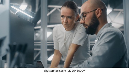 Engineers Reviewing Network Performance Data. Male and Female IT Engineer Team Collaborating Over Computer Monitor to Review Critical Network Performance Metrics. Teamwork and Real Time IT Monitoring.