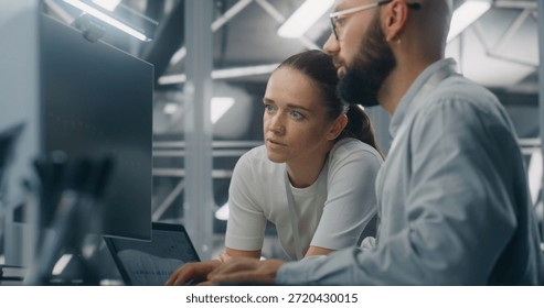 Engineers Reviewing Network Performance Data. Male and Female IT Engineer Team Collaborating Over Computer Monitor to Review Critical Network Performance Metrics. Teamwork and Real Time IT Monitoring.