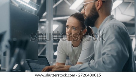 Engineers Reviewing Network Performance Data. Male and Female IT Engineer Team Collaborating Over Computer Monitor to Review Critical Network Performance Metrics. Teamwork and Real Time IT Monitoring.