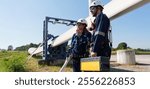 Engineers in safety gear conduct a detailed inspection of wind turbine blades at a construction site. Large blades are placed on the ground, highlighting the renewable energy technology.