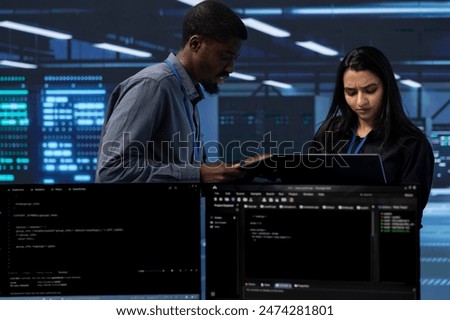 Engineers in server farm checking recovery plan, monitoring tech equipment energy consumption. Coworkers in data center workspace doing routine disk checks using laptop and tablet