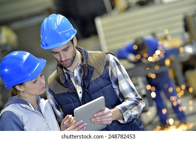 Engineers in steel factory working on digital tablet