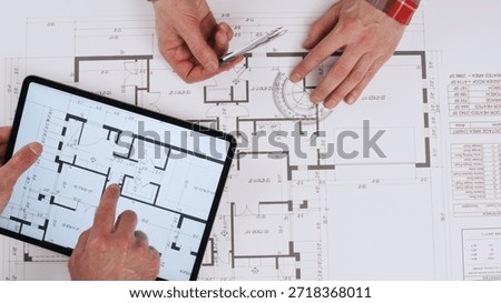 Engineers take measurements and notes while working on a paper drawing of the house, while the builder uses an electronic version of the drawing on a tablet.