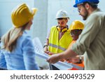 Engineers team with draft plan of building and tablet talking constructing site. Construction manager and engineer working on building site. Team of construction workers discussing
