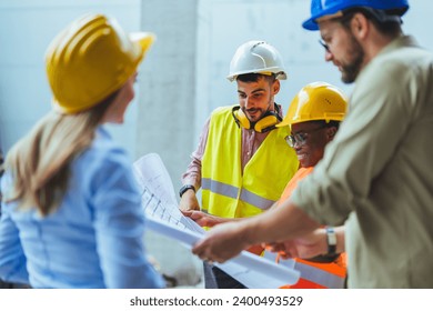 Engineers team with draft plan of building and tablet talking constructing site. Construction manager and engineer working on building site. Team of construction workers discussing
