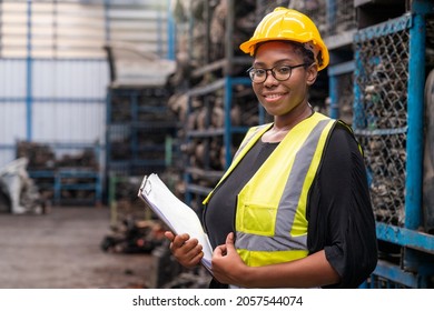 Engineers or technicians are inspecting auto parts in warehouses and factories. African american woman holding a flipchart in parts warehouse. - Shutterstock ID 2057544074