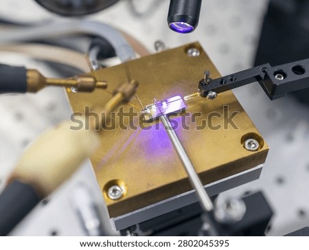 Engineers test semiconductor chip performance in clean laboratory environment using precision instruments and UV light inspection tools.