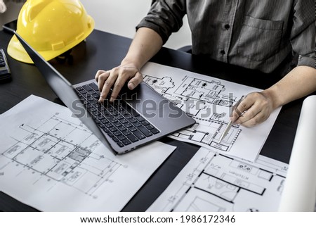Engineers are typing on a laptop keyboard to review the design of the house before editing it and sending it to customers. Home design ideas by expert engineers for quality and correct homes.