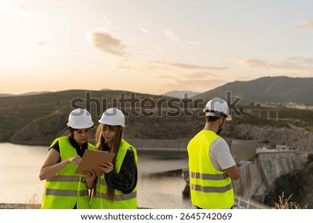 Engineers using digital tablet and laptop at dam construction site