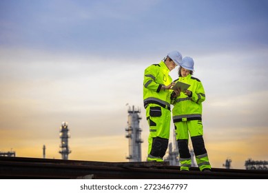 Engineers Using Digital Tablet for Technical Inspection at Oil Refinery Site During Twilight, Multi-Ethnic Engineering Team Collaborating on Energy Project at Industrial Plant Background