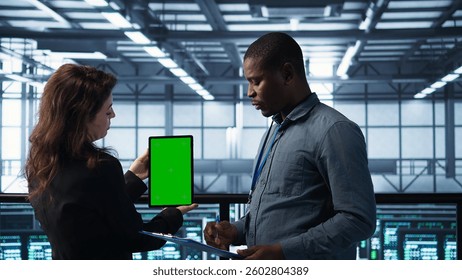 Engineers using green screen tablet in data center, checking infrastructure reliability, writing in clipboard. Workers using mockup device in server room, managing server virtualization, camera B
