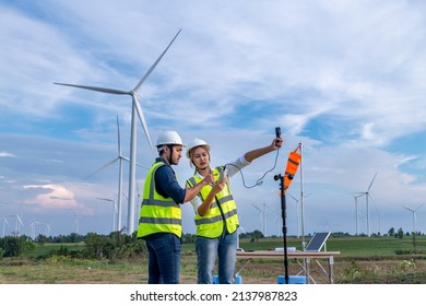 Engineers using meteorological or anemometer instrument collect data laptop to measure the wind speed, temperature,humidity and solar cell system on wind turbine station is sustainable energy concept