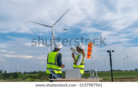 Engineers using meteorological and drone instrument collect data laptop to measure the wind speed, temperature,humidity and solar cell system on wind turbine station is sustainable energy concept.