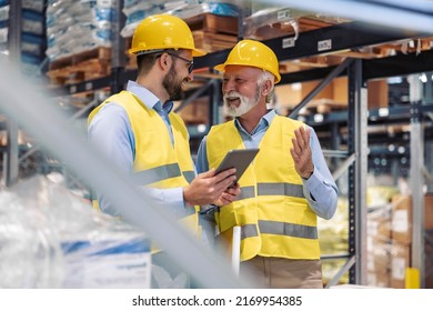 Engineers walking through large warehouse center. They are checking shelves full with boxes and products. Warehouse workers using digital tablet. - Powered by Shutterstock