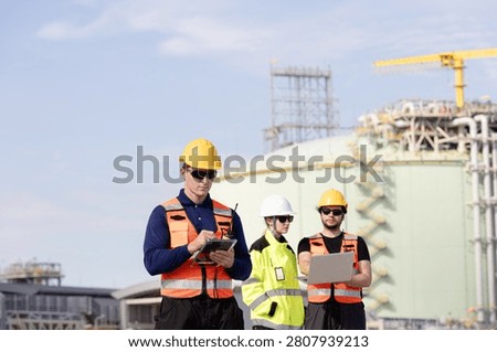 Engineers and workers collaborating on construction site with safety gear and equipment in industrial setting
