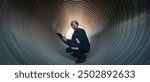 Engineers working inside a large steel pipe of a tunnel foundation. Workers involved in constructing a pipeline for transporting oil, natural gas, and fuel at an industrial factory.