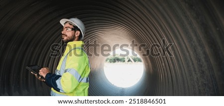 Engineers working inside a large steel pipe of a tunnel foundation. Workers involved in constructing a pipeline for transporting oil, natural gas, and fuel at an industrial factory.