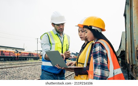 Engineers Working On Railway Train Statation And Holding Laptop For Plan And Meeting. Portrait Of Professional Leadership Of Engineering Teamwork. Warehouse And Successful Concept. 