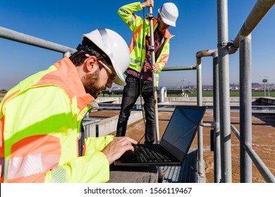 Engineers working on water treatment plant with laptop and measuring sensors