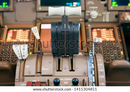 Engines thrust levers inside a big jet plane cockpit.