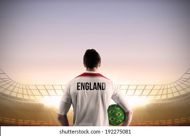 England Football Player Holding Ball Against Large Football Stadium Under Blue Sky