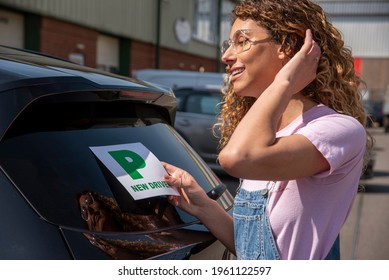 England, UK. 2021.  New Driver, Young Attractive Woman Holding A Green New Driver Sign To Display On Her Car After Passing The Driving Test.