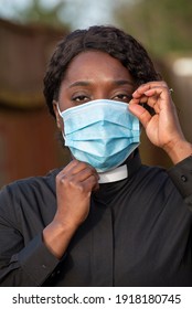 England, UK, December 2020. A Black Minister Wearing A Protective Medical Mask And White Collar During Coronavirus Outbreak