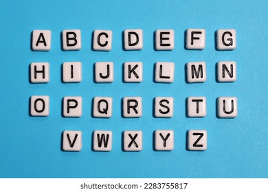 English alphabet. Beads white tiles on a blue background.