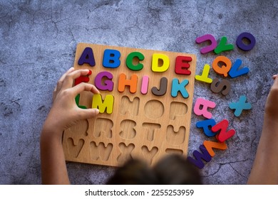 English alphabet made of square wooden tiles with the English alphabet scattered on hand. The concept of thinking development, grammar - Shutterstock ID 2255253959