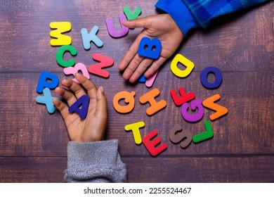 English alphabet made of square wooden tiles with the English alphabet scattered on hand. The concept of thinking development, grammar - Shutterstock ID 2255524467