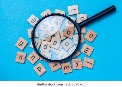 English alphabet made of square wooden tiles with the English alphabet scattered on blue background. The concept of thinking development, grammar.