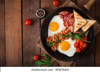 English breakfast - fried egg, beans, tomatoes, mushrooms, bacon and toast. Top view - Shutterstock ID 393676441