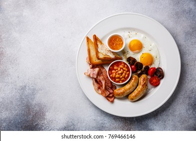 English breakfast with fried egg, sausage, bacon, beans and toast on white background copy space 