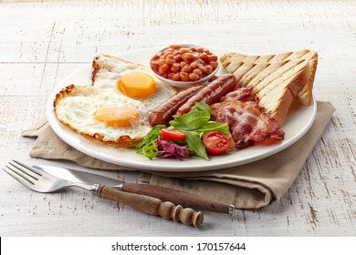 English breakfast with fried eggs, bacon, sausages, beans, toasts and fresh salad - Shutterstock ID 170157644