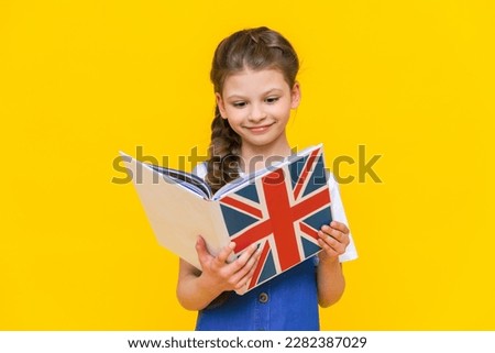 English for children. A little girl holds a textbook with an English flag in her hands. Children's language education. Yellow isolated background. Foto stock © 