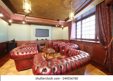English Cigar Room With Red Leather Armchairs And Home Theater System.