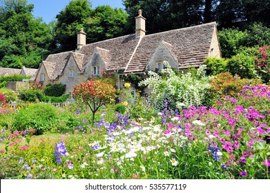 English Country Cottage with beautiful flowers garden in the sunshine in Cotswolds, England, UK