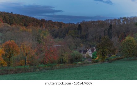 English Countryside Cottage With Autumn Treeline In A Smooth Green Space 