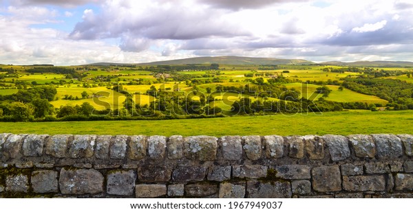 English countryside and farmland landscape\
panorama background along Hadrian\'s Wall Roman ruin. Beautiful\
rural country side pastures in\
England