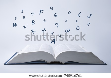 English dictionary with letters flying out of it on a white background.