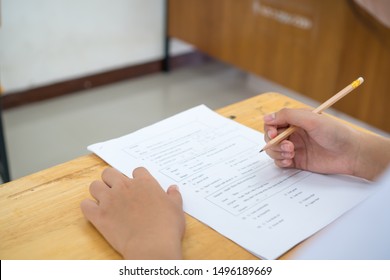 English Exams Test Student In School, University Students Holding Pencil For Testing Exam Writing Answer Sheet Or Exercise For Taking In Assessment Paper On Table Classroom. Education Study Concept