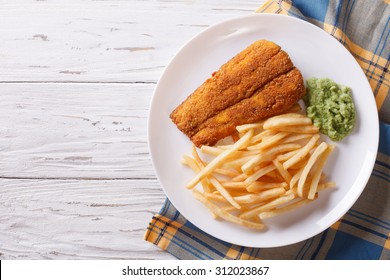 English Food: Fried Fish In Batter With Chips And Pea Puree On A Plate. Horizontal View From Above
