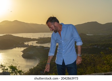 English Harbour, Antigua - July 3, 2021: Image Of An Attractive Older Man Looking Away From The Camera Pointing Down At The Ground At Shirley Heights In Antigua. 