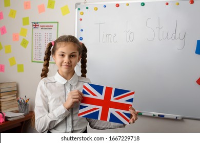 English Learner Of Secondary School Holds Union Jack Flag Standing In Classroom Of Conventional School