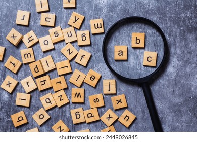 English letters scattered on grey background. Ideas for developing grammatical thinking and learning English, Magnifying glass with letters in English letters